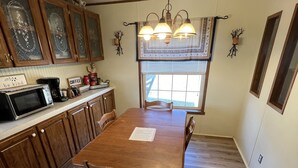 A kitchen with wooden cabinets, a dining table, and a chandelier.