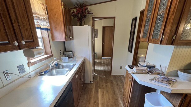 A kitchen with wooden cabinets, a dishwasher, a stove, and a trash can.
