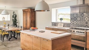 Una cucina moderna con isola centrale, mobili in legno, piano cottura a gas e schienale decorato.