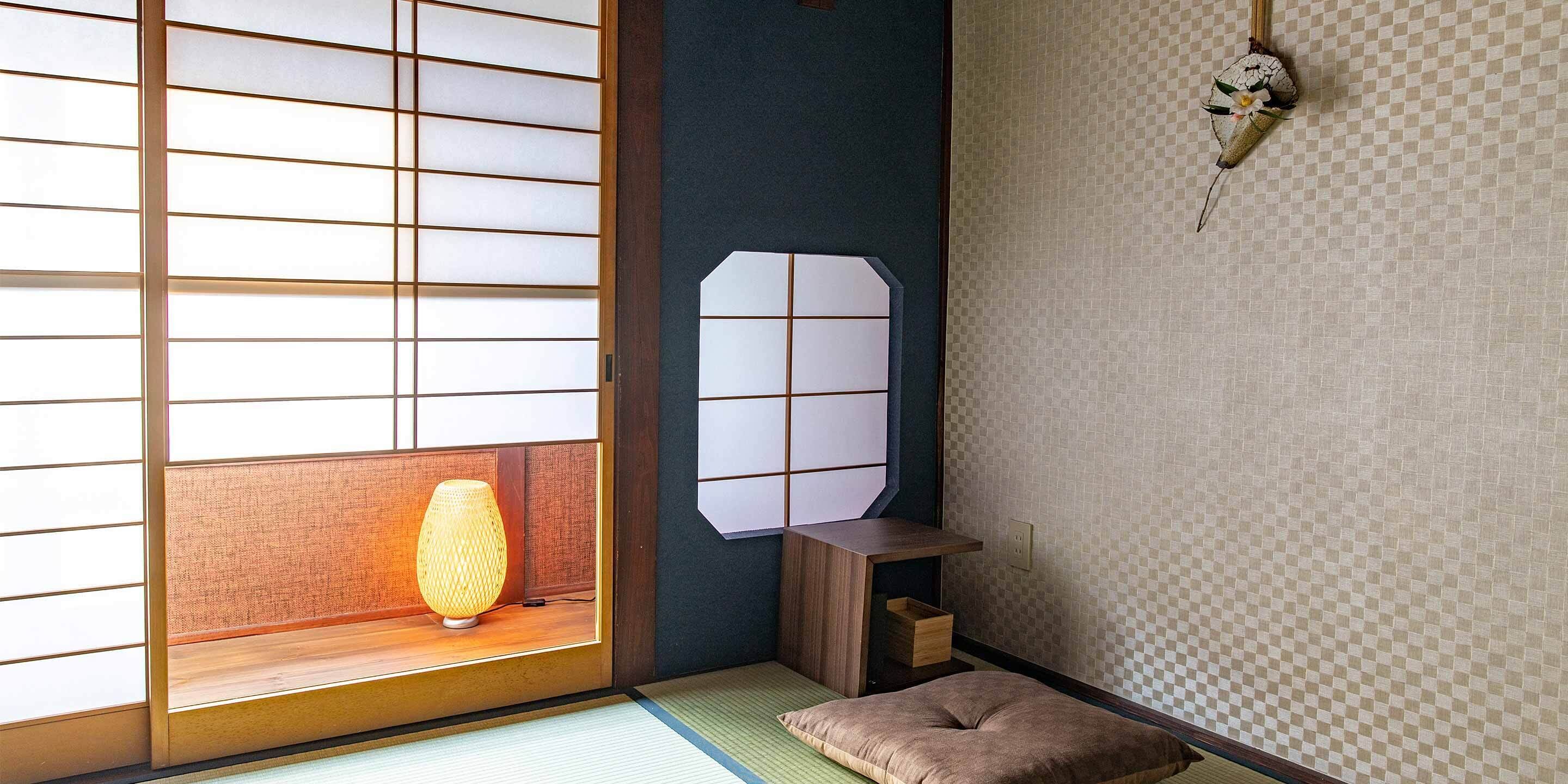 Een traditionele Japanse kamer met tatami vloerbedekking, een shoji schuifwand, een lage houten tafel en een klein zitbankje.