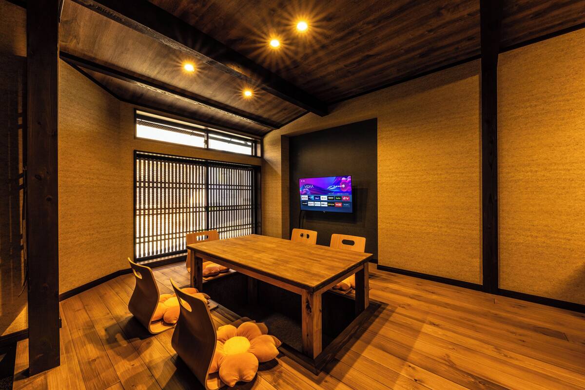 A modern room with a wooden table, chairs, and a television on the wall.