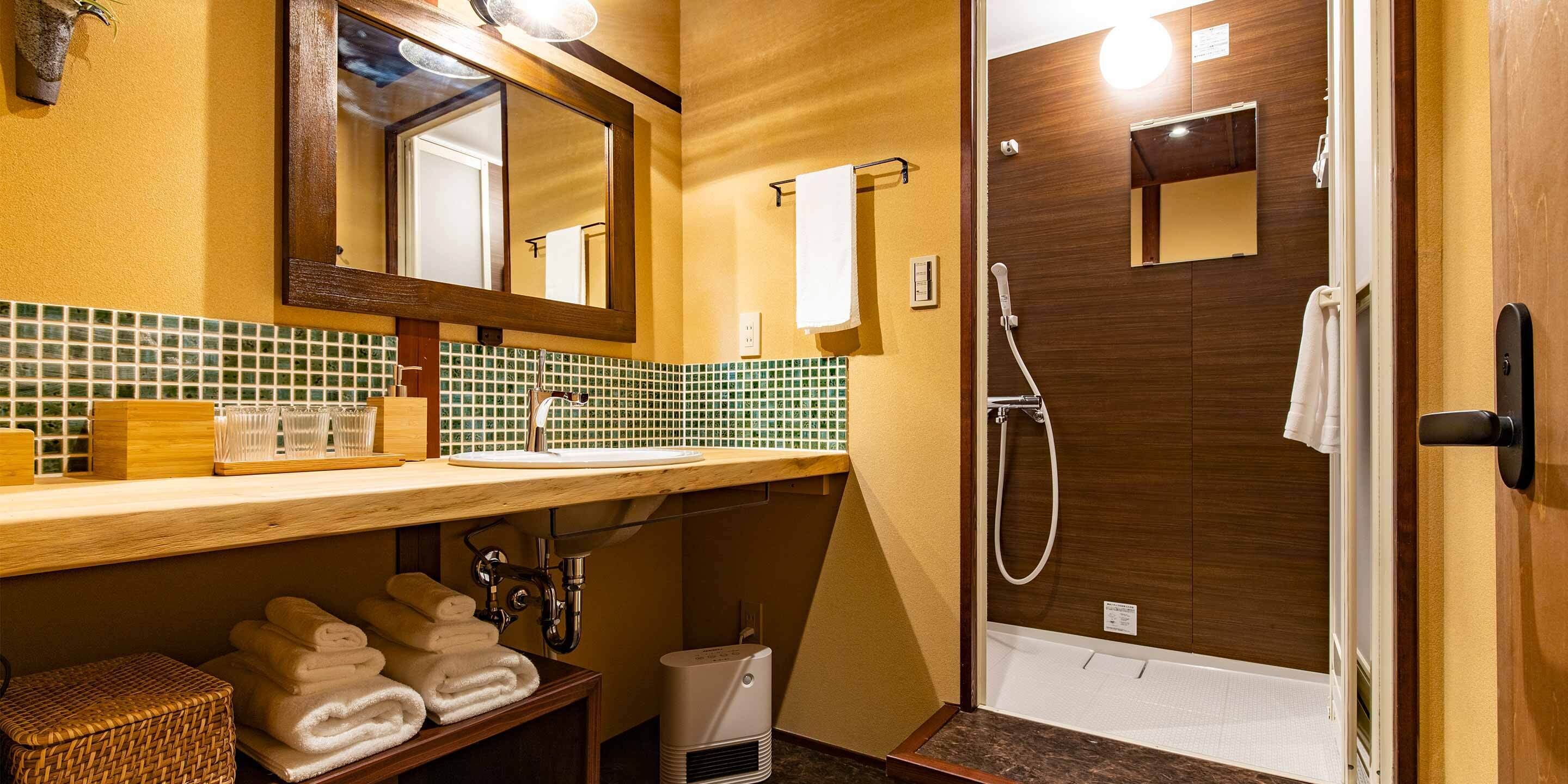 Une salle de bain avec un meuble-lavabo en bois, un miroir, un lavabo, une douche et un porte-serviettes.