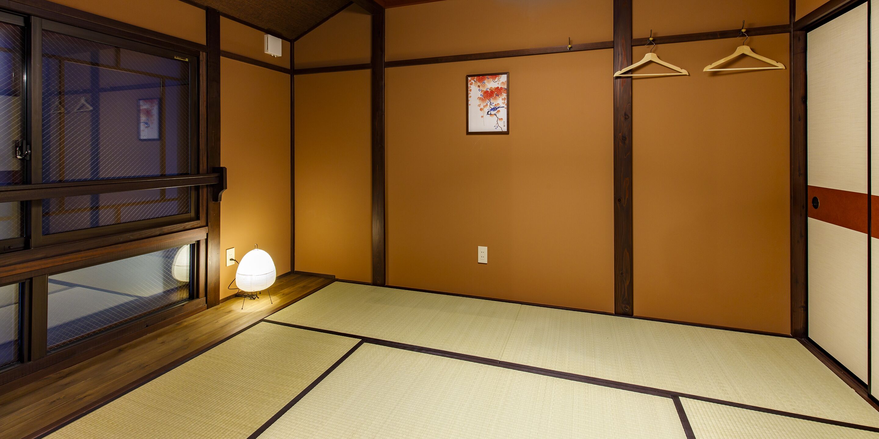 Ein traditioneller japanischer Raum mit Tatami-Bodenbelag, Shoji-Schirm und einer hängenden Leuchte.