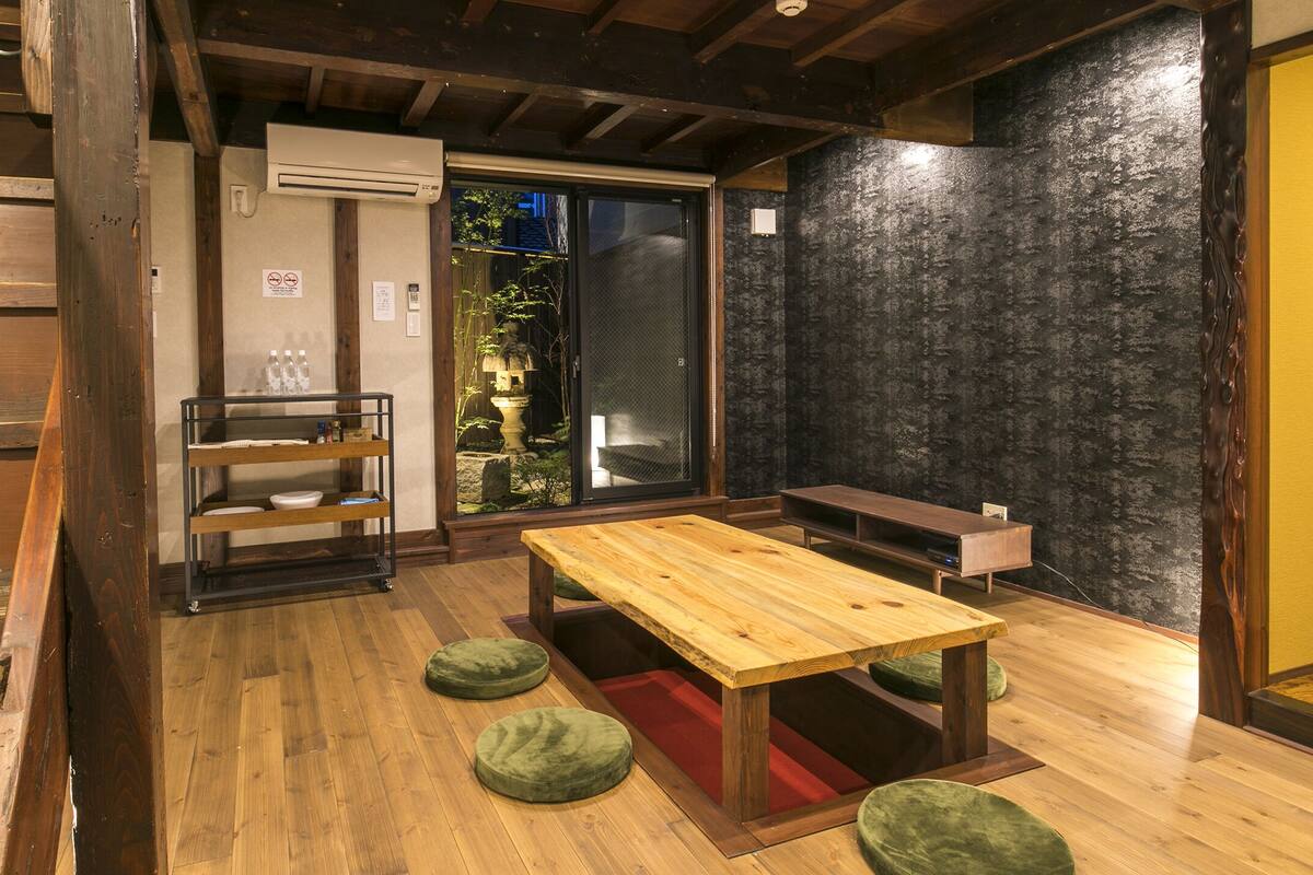A wooden interior with a table, benches, and a shelf with bottles.