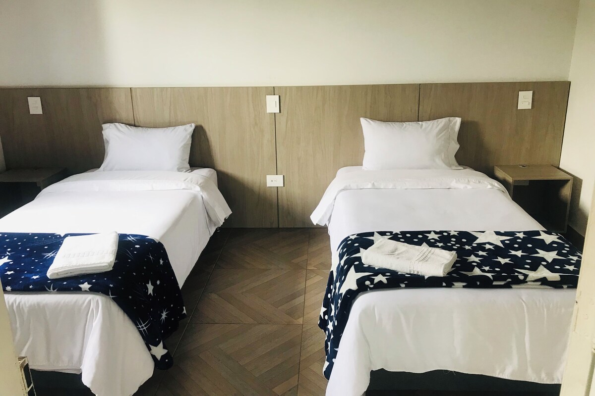 Two single beds with white bedding and star-patterned blankets, wooden headboards, and bedside tables.