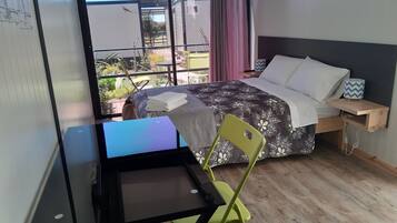 A hotel room with a bed, a desk, a chair, and a view of the outside.