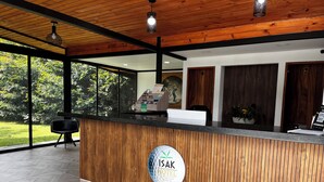 Mostrador de recepción con detalles de madera, un logotipo y vistas a zonas verdes.