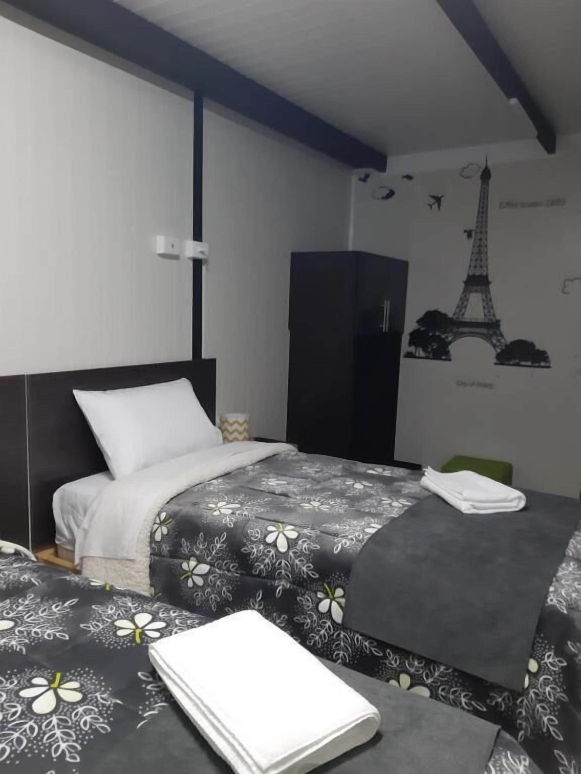 A bedroom with a bed, a wardrobe, and a wall decal of the Eiffel Tower.