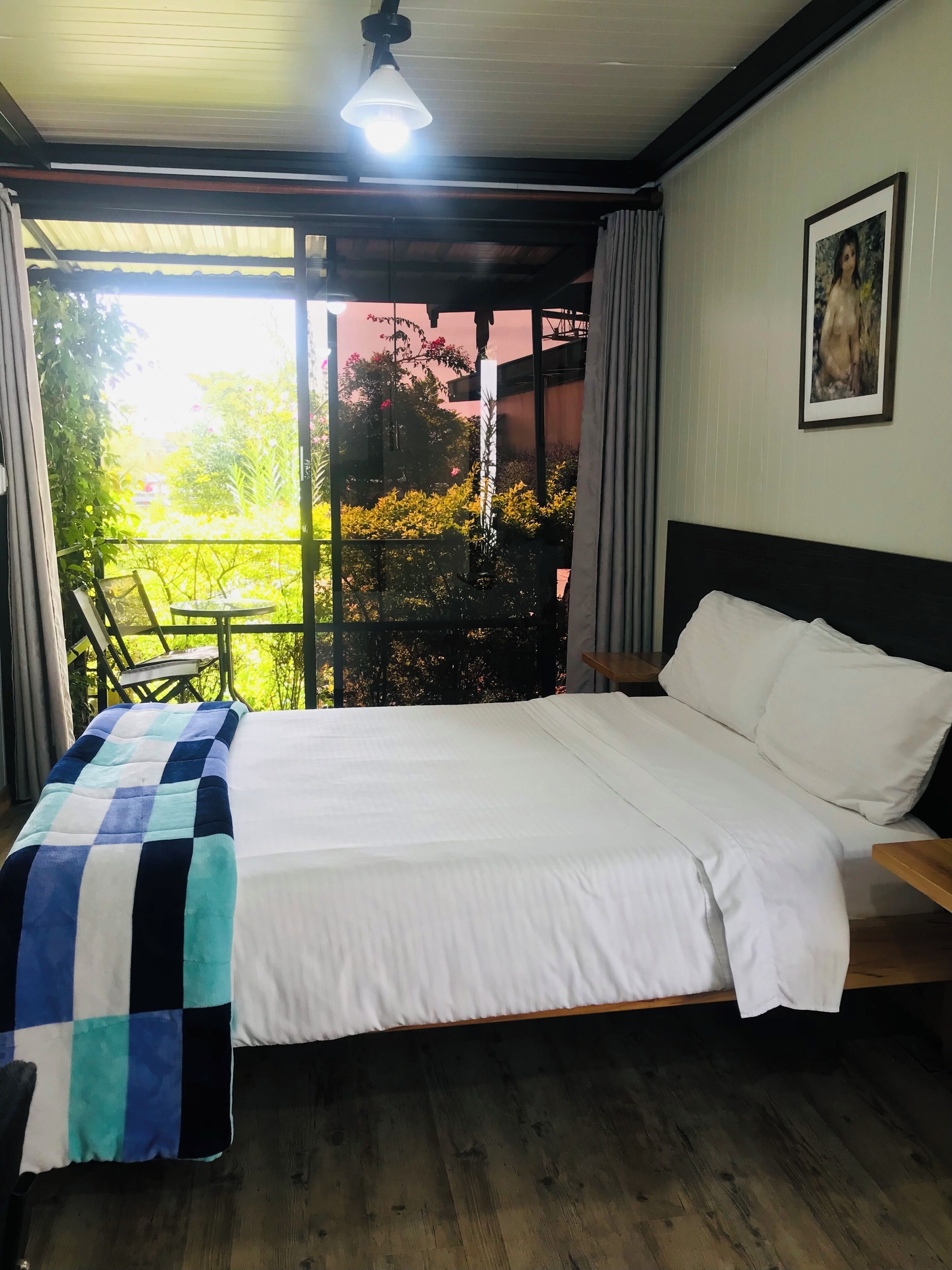 A bedroom with a bed, a nightstand, a chair, a window, and a ceiling fan.