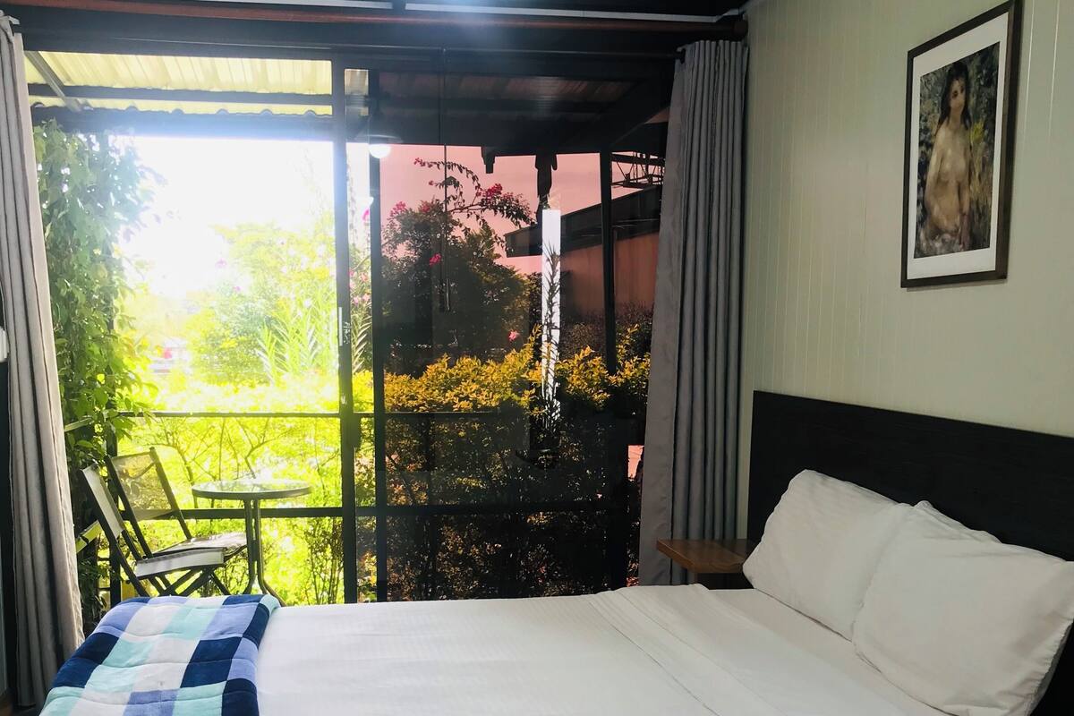 A bedroom with a bed, a nightstand, a chair, a window, and a ceiling fan.