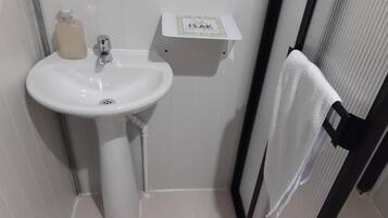 Un baño con un lavamanos blanco, un dispensador de jabón y un porta papel higiénico con el rótulo 'ISAK'.