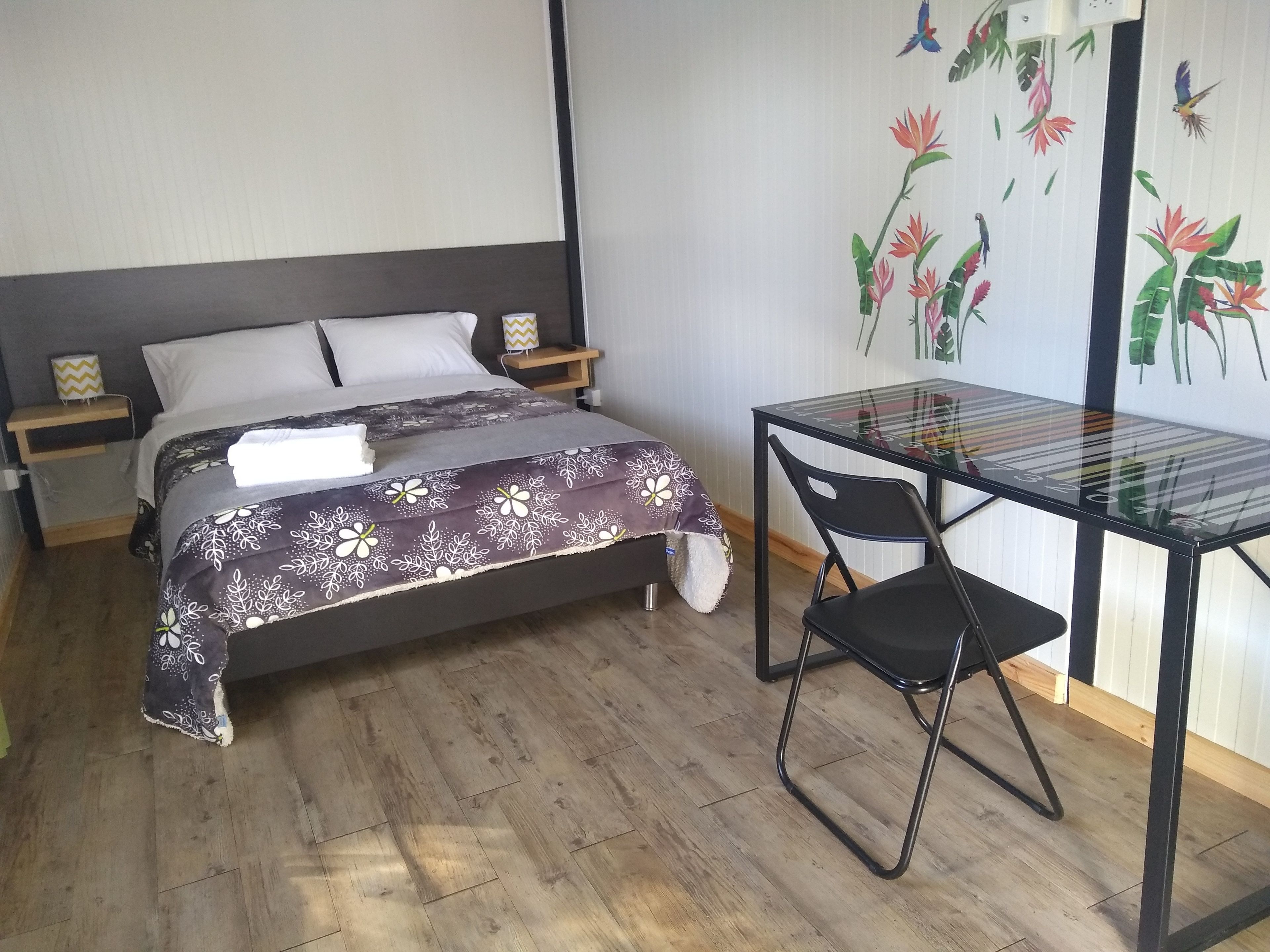 A bedroom with a bed, bedside tables, a desk, and a chair.