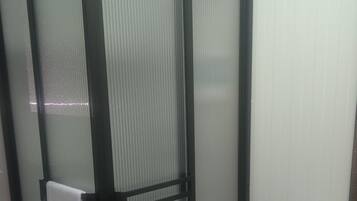 Un baño con inodoro, cabina de ducha y una toalla colgada en la puerta.