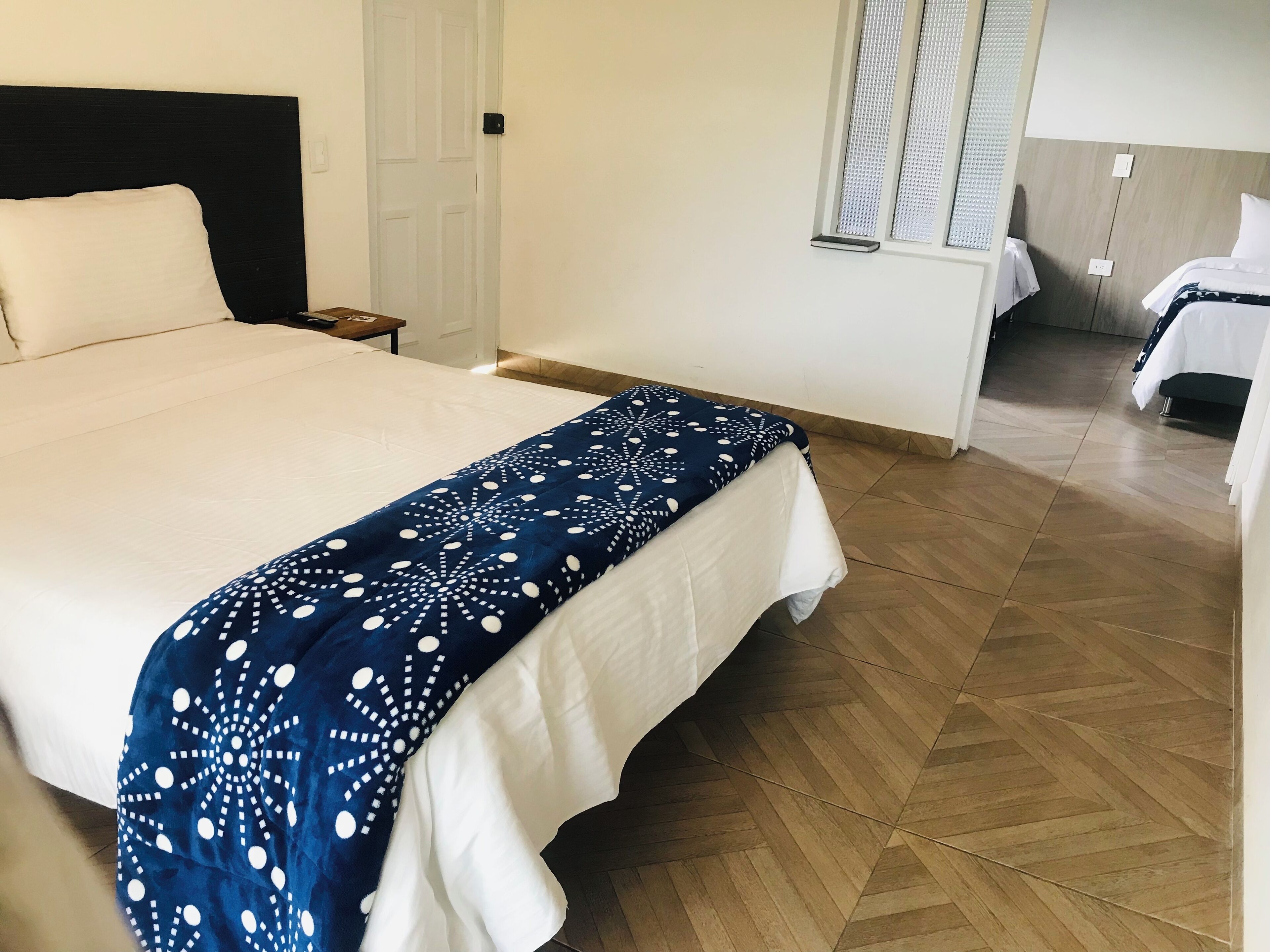 Une chambre d’hôtel avec un grand lit, une table de chevet, une commode et une fenêtre avec des stores.