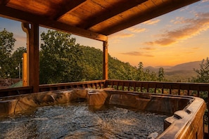 Un jacuzzi bajo una pérgola de madera con vistas a un paisaje boscoso.