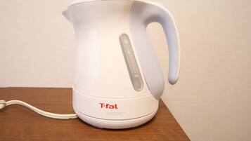 A white electric kettle with a handle and control panel, placed on a wooden surface.
