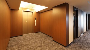Un pasillo con paredes de madera y pisos alfombrados, que incluye un ascensor y una puerta con un letrero.