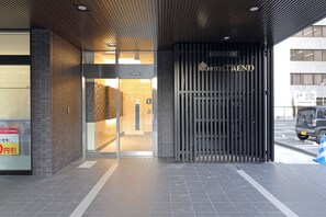 L’entrée d’un hôtel au design moderne, avec une porte en verre et une enseigne indiquant « HOTEL TREND ».