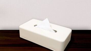 A white tissue box on a wooden surface against a plain wall.