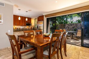 A spacious kitchen with wooden cabinets, a stainless steel refrigerator, and a dining area with a wooden table and chairs.