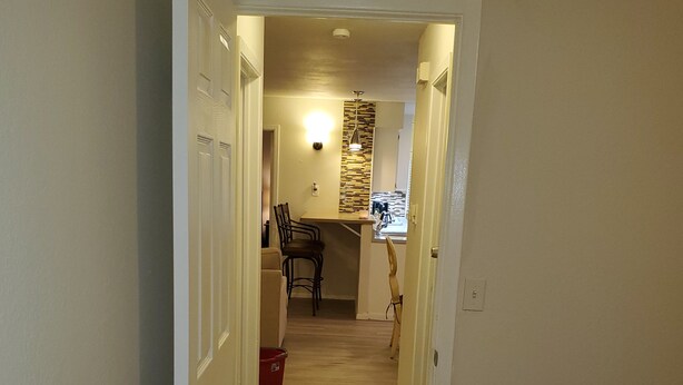 Un couloir étroit mène à une cuisine équipée d’une table et de chaises.