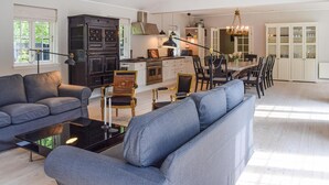 Un salón espacioso con sofá, una mesa de centro y una zona de comedor con sillas y una mesa.