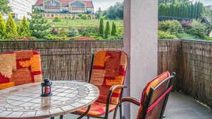 A round table with four chairs, a metal chair, and a small table lamp. - 1 bedroom cozy apartment in Ostroda (Ostroda)