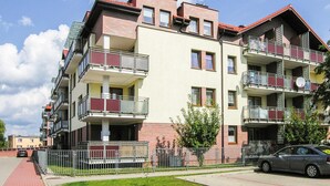 A multi-story residential building with balconies, a brick facade, and a flat roof. - 1 bedroom cozy apartment in Ostroda (Ostroda)