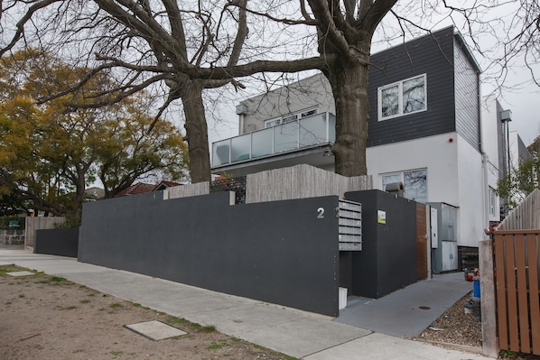 A modern two-story house with a black exterior, a visible number '2' on the wall, and a tree in the foreground.