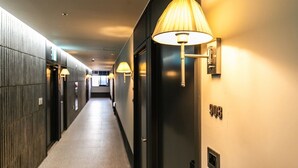 A hotel hallway with a long corridor, wall-mounted lamps, and a door with the number 908. - Brown Dot Hotel Jinju Chungmugong (Jinju)
