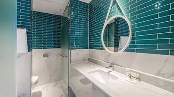 Un baño moderno con cabina de ducha de vidrio, lavamanos de mármol y mosaicos azules.