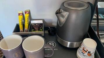 A tray with a French coffee creamer, a box of coffee creamer, a French press coffee maker, and two mugs with a logo.