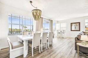 Un vaste espace de vie comprenant une table à manger, des chaises, un canapé et un lustre.