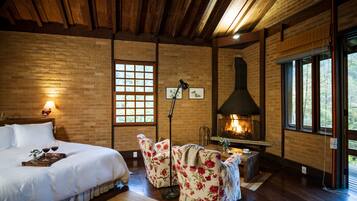 A room with a bed, a fireplace, and a large window.