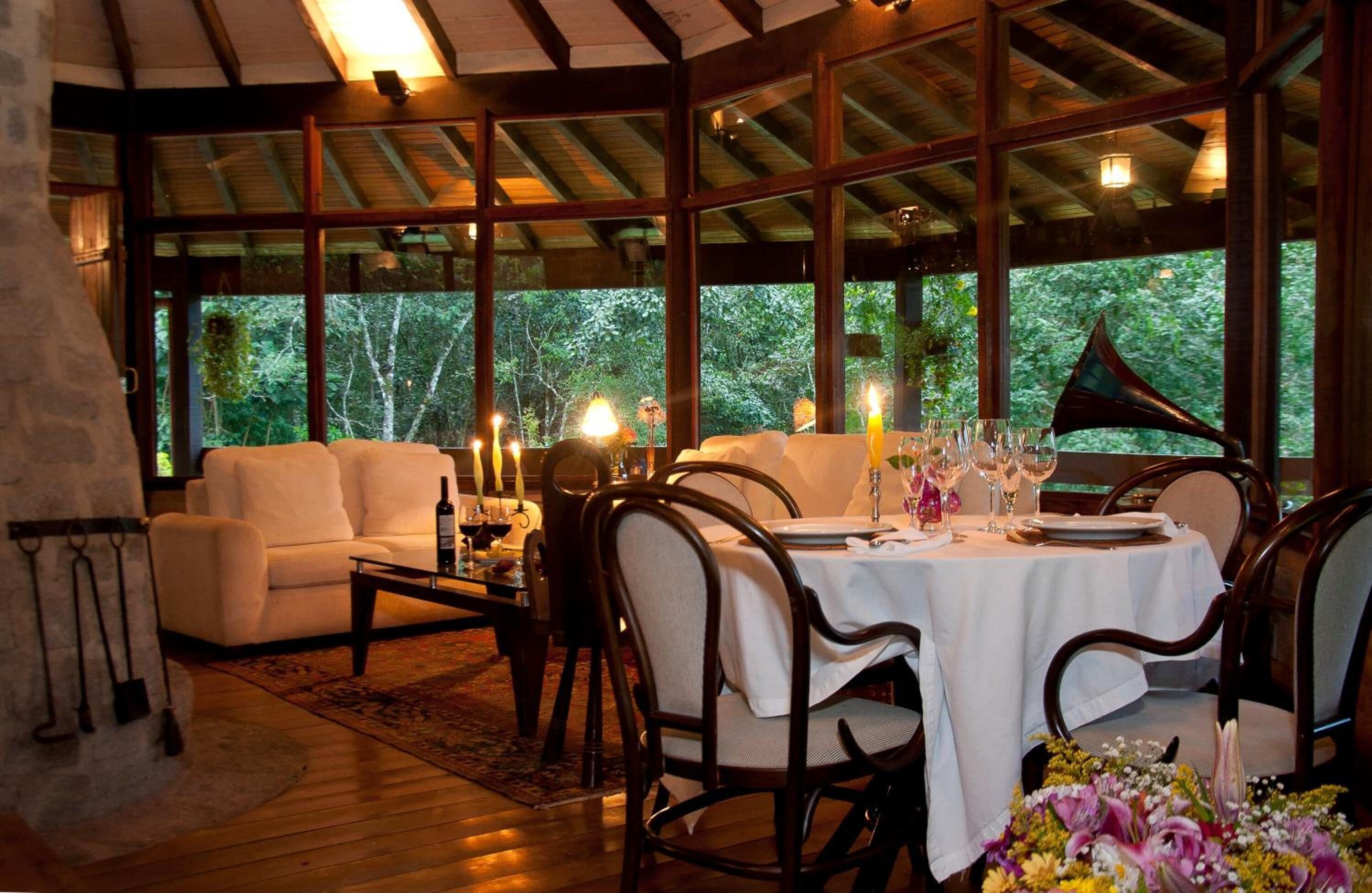 A cozy dining area with a white table set for two, surrounded by wooden chairs. A white sofa and a wooden coffee table are also visible.