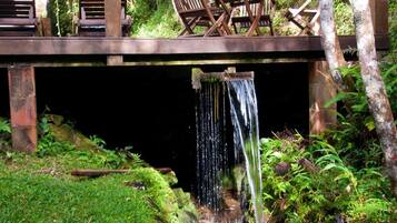 A wooden deck with chairs and a table overlooking a waterfall.