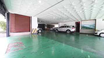 A parking garage with a green floor, white ceiling with circular patterns, and a large wooden door on the left.