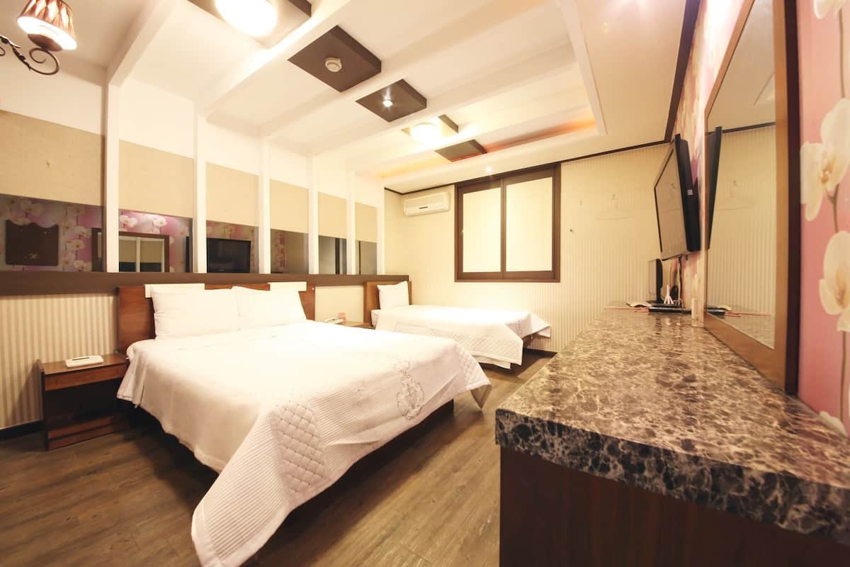A hotel room with two beds, a marble countertop, a television, and a large window.