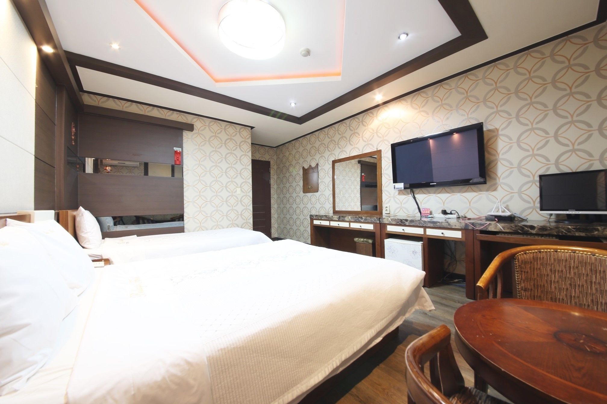 Een hotelkamer met een groot bed, een bureau met een flatscreen-tv, een spiegel en een stoel.