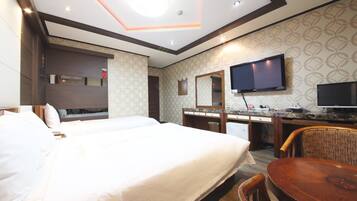 Een hotelkamer met een groot bed, een bureau met een flatscreen-tv, een spiegel en een stoel.