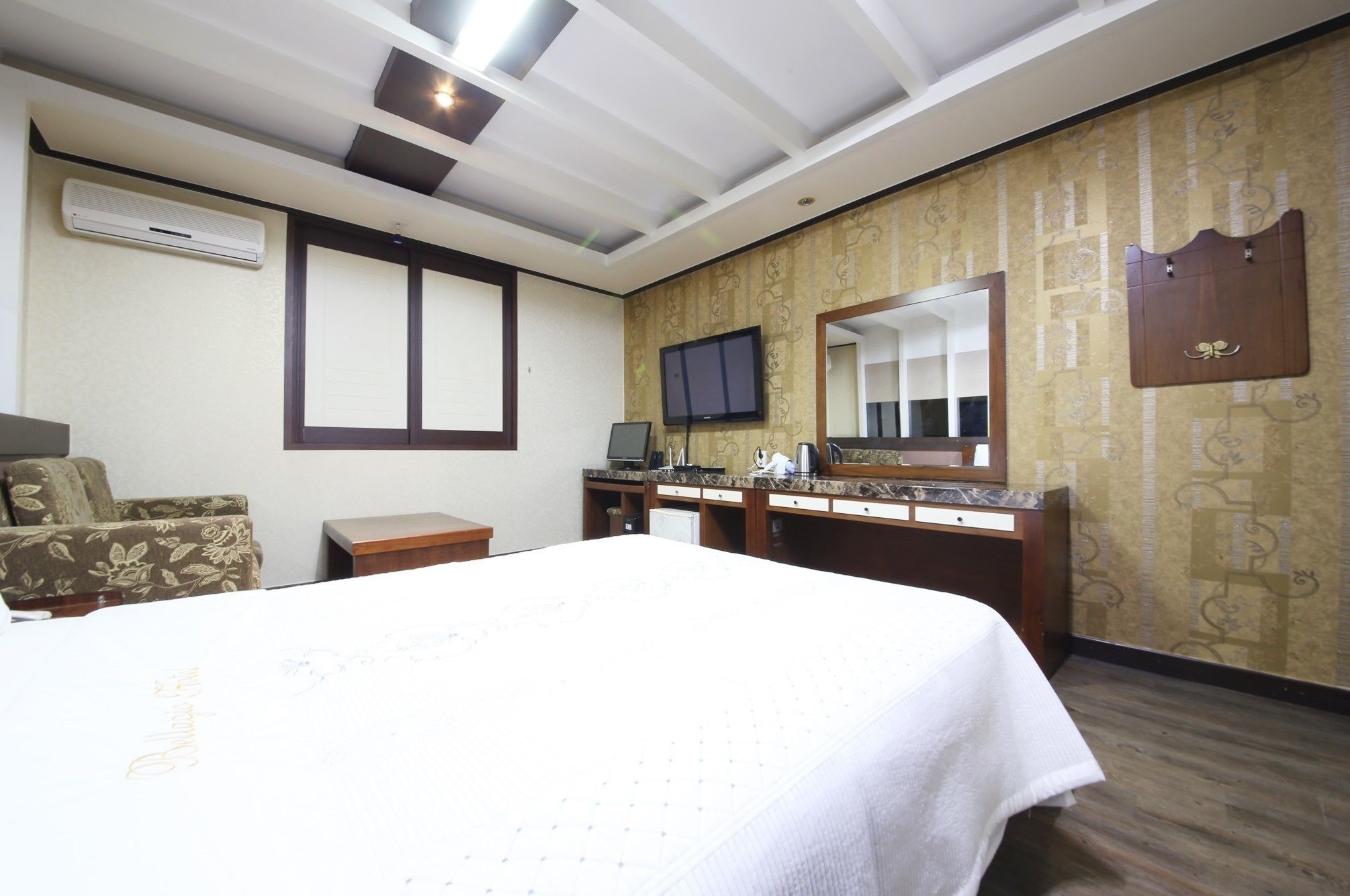 Une chambre d’hôtel avec un lit, un bureau avec un ordinateur, une télévision et un miroir.