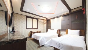 Une chambre d’hôtel avec deux lits, un plancher en bois, un comptoir en marbre et une grande fenêtre.