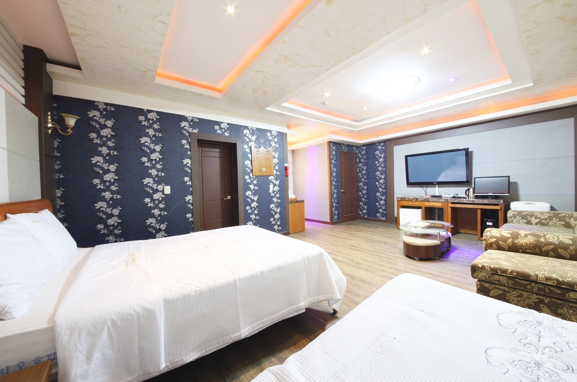 Een hotelkamer met twee bedden, een televisie, een bureau en een bank.