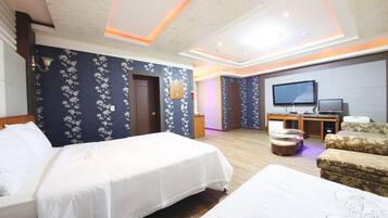 Una habitación de hotel con dos camas, televisión, escritorio y sofá.