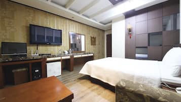 A hotel room with a bed, a desk, a television, a mirror, and a wardrobe.
