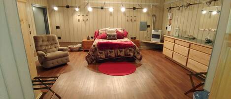 A bedroom with a bed, a chair, a dresser, and a mirror.