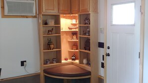 A compact kitchen with wooden cabinets, a built-in bench, and a small window.