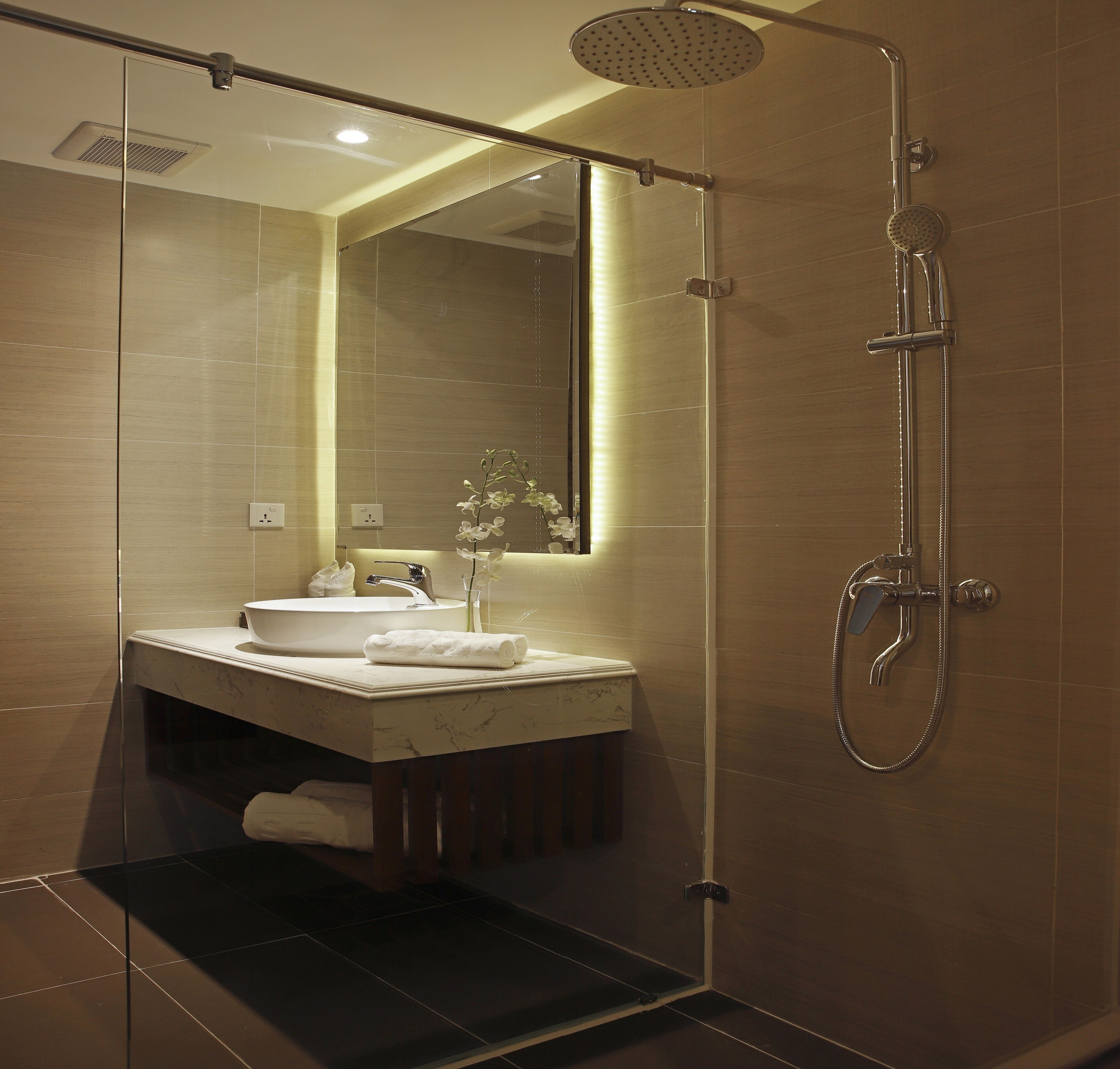 A modern bathroom with a glass-enclosed shower, a marble sink, and a large mirror.