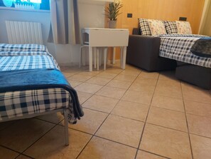 A hotel room with two beds, a small table, a chair, and a potted plant. - Palazzo Ponte Pietra (Verona)