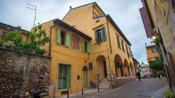 Eine schmale Kopfsteinpflasterstraße, gesäumt von historischen Gebäuden mit rundbogigen Hauseingängen und grünen Fensterläden.